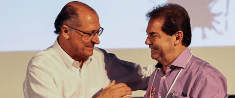 Geraldo Alckmin cumprimenta Paulinho da força. Alckmin veste camisa social azul clara e Paulinho está de camisa social vinho, com crachá.