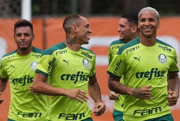 Jogadores do palmeiras correm enquanto sorriem durante treinamento