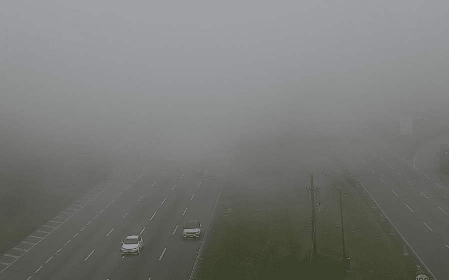 Foto mostra carros saindo do meio da neblina e fumaça impedindo visibilidade mais distante, cobrindo as duas pistas.