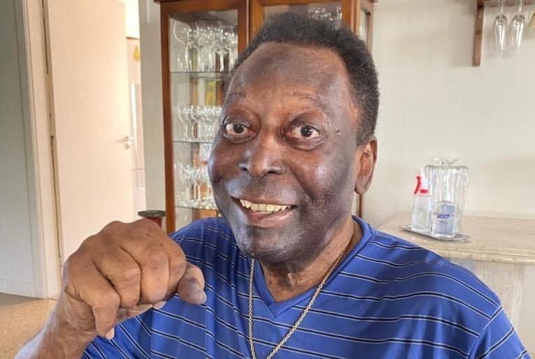 Pelé, senhor negro, faz gesto com o punho cerrado para a câmera.