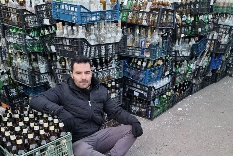 Arthur do Val sentado ao lado de pilhas de garrafas de vidro, supostamente usadas para fabricar os coquetéis molotov, bombas incendiárias.