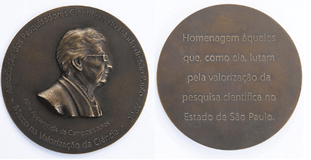 Imagem mostra duas faces da medalha, uma com o busto de um homem e outra com uma mensagem escrita.
