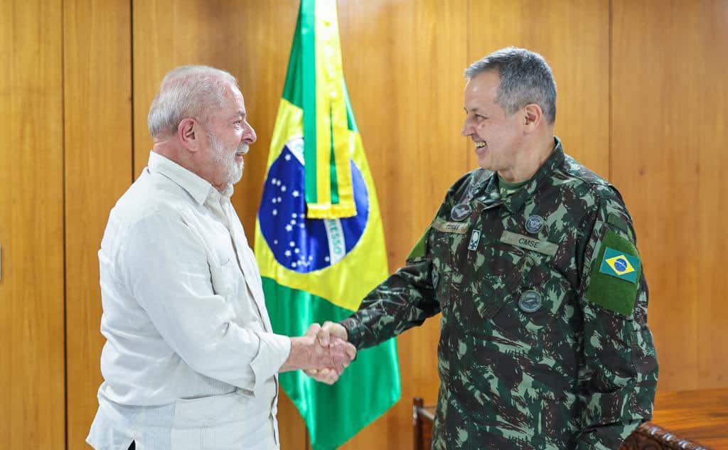 Lula, de camisa social, estende a mão e cumprimenta o novo comandante do exército, Tomás Miguel.