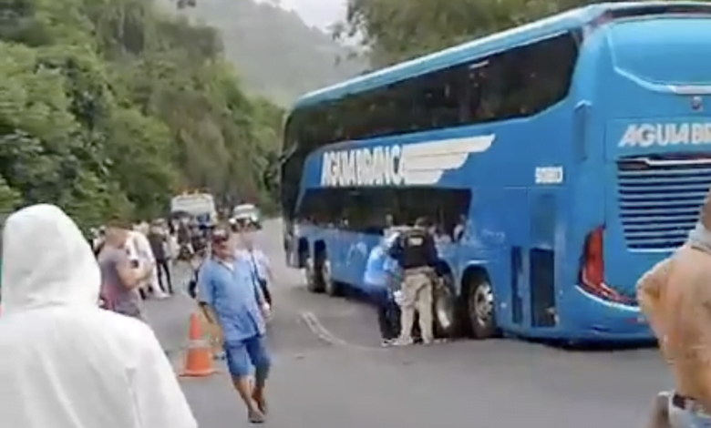 Imagem mostra pessoas no meio da rodovia enquanto ônibus está com duas rodas traseiras dentro do desnível provocado pelo afundamento do asfalto.