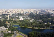 Visão aérea do Parque do Ibirapuera, em São Paulo. Imagem traz a lagoa em primeiro plano, com e prédios ao fundo compondo a paisagem