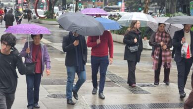 Pedestres usam agasalhos em dia nublado na cidade de São Paulo